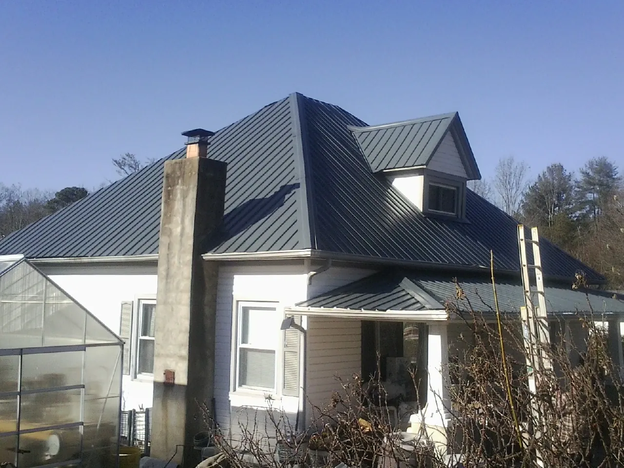 Dark blue standing seam metal roof on a white farmhouse with dormer — Slate & Tile Roof Repair by Roofing Brothers in Perryopolis