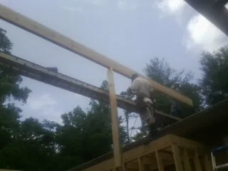 Carpenter setting a ridge beam over a new addition frame — Ice Dam Removal by Roofing Brothers in Perryopolis