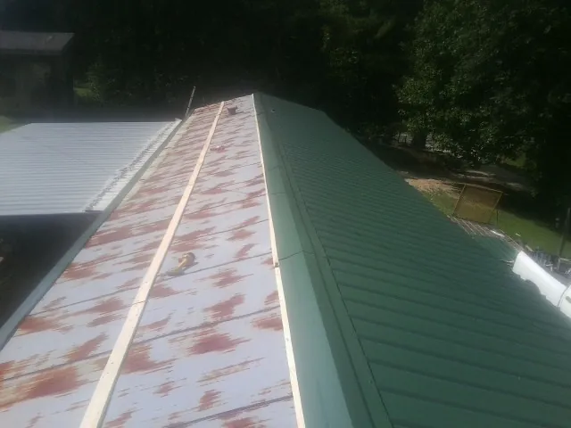 Old rusted panels beside newly installed green metal roofing — Wind Damage Roof Repair by Roofing Brothers in Perryopolis