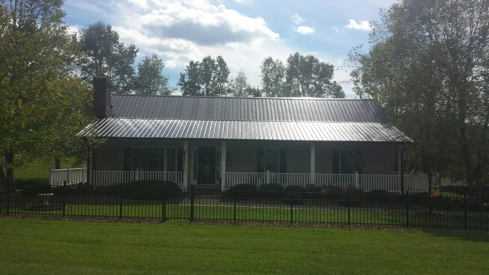 Gray metal roof on a brick ranch with a full width front porch — Gutter Guard Installation work by our crew in Perryopolis
