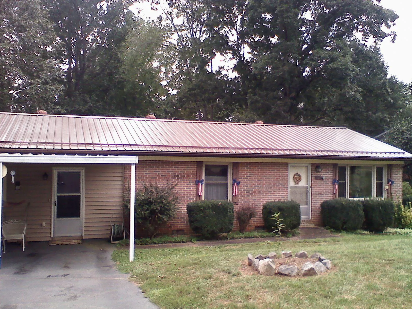 Bronze metal roof and carport on a brick ranch home — Roof Repair work by our crew in Perryopolis