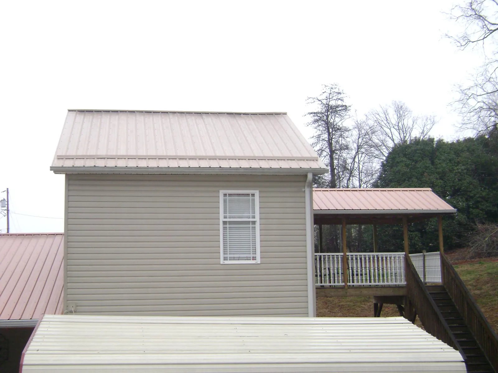 Tan metal roofs on a two story addition and attached porch, from a Roof Replacement job in Perryopolis