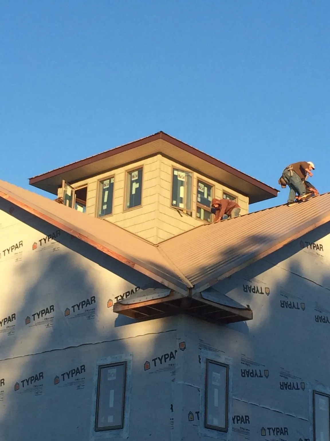 Roofers working around a rooftop cupola on a new metal roof at sunset — Roof Waterproofing in Perryopolis by Roofing Brothers